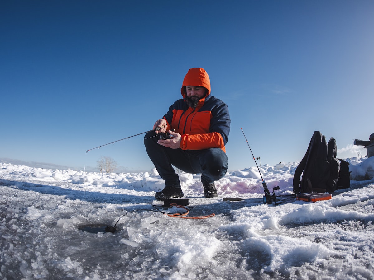 An angler ice fishing on a frozen lake